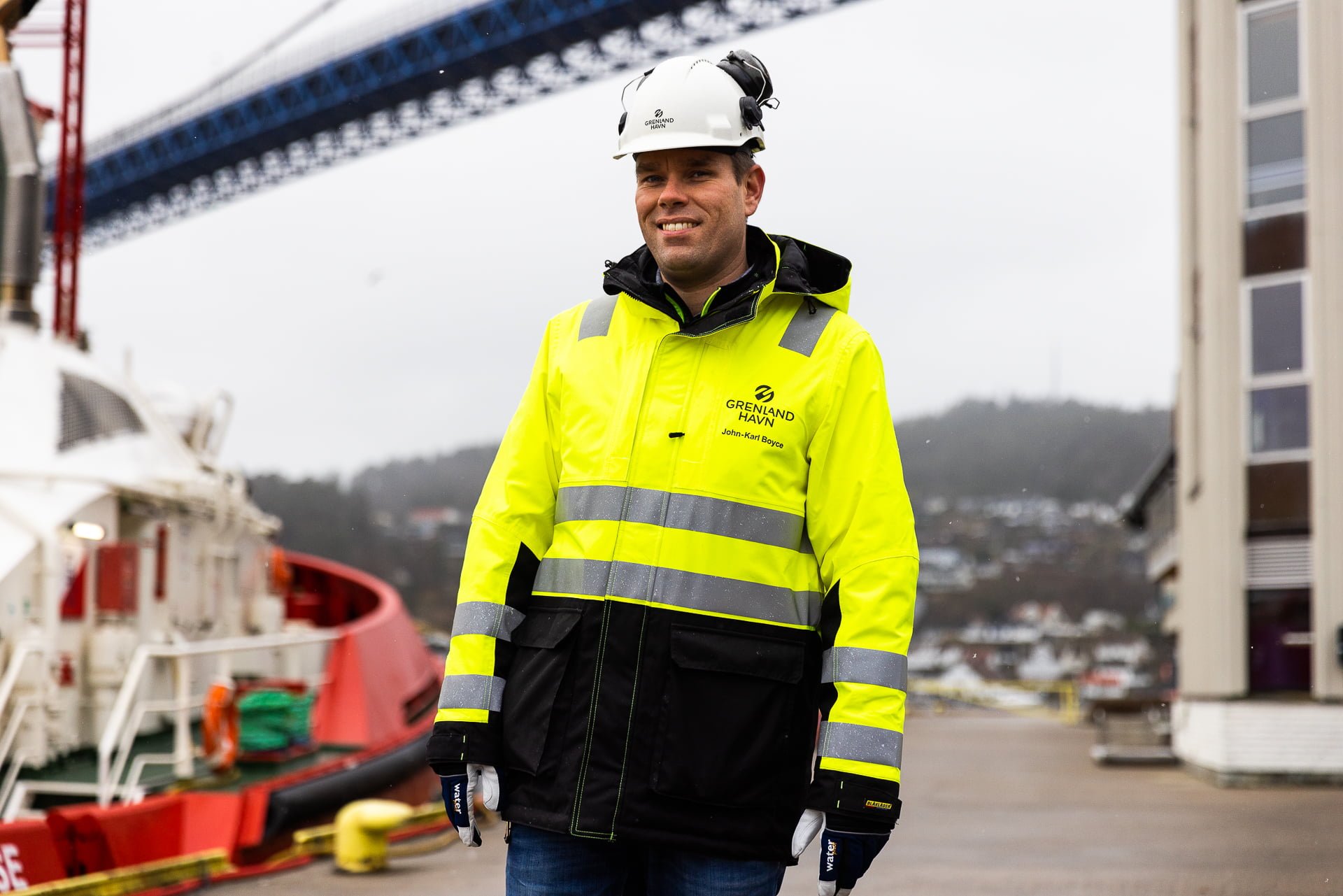 Miljøleder i Grenland Havn John-Karl Boyce står foran tauebåt og med Breviksbrua i bakgrunnen